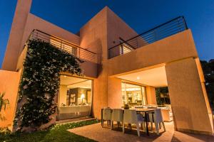 une maison avec une table et des chaises devant elle dans l'établissement Al Maaden 132 - Luxury front line golf villa with heated pool, à Marrakech