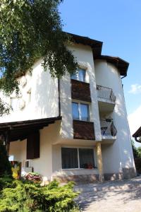 a white building with windows and a tree at Hotel Radi in Sapareva Banya