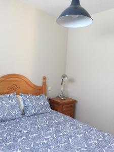 a bedroom with a bed with a blue comforter and a lamp at Las Olivas in Candeleda