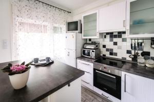 a kitchen with white cabinets and a black counter top at Csuka48 Apartman in Szarvas +19 photos