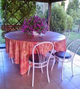 una mesa con sillas y un jarrón de flores púrpuras en Aranysellő Vendégház, en Abádszalók