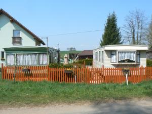 ein Haus mit einem orangenen Zaun neben einem Haus in der Unterkunft Ubytovani v mobilnim domku in Sobotka