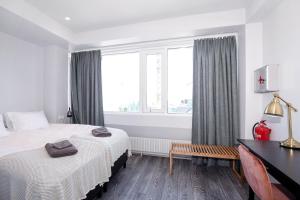 a bedroom with two beds and a desk and a window at Svala Apartments by Heimaleiga in Reykjavík