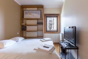 sypialnia z łóżkiem, telewizorem i oknem w obiekcie Deluxe Condominium with Ocean View w Porto