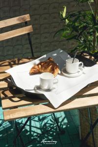 a table with two cups of coffee and a croissant at Oki Doki Studios in Milan