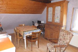 a dining room with a table and chairs and a cabinet at Gîte rustique sous combles in Merxheim