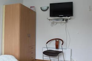 una camera da letto con sedia e TV a parete di Fosstún Guesthouse a Skogar