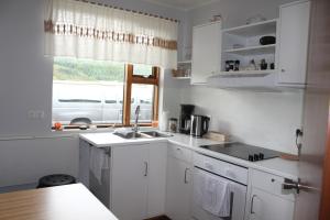 uma cozinha com armários brancos, um lavatório e uma janela em Fosstún Guesthouse em Skógar