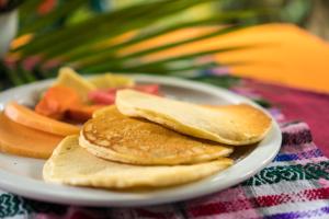 a plate of pancakes and fruit on a table at Hotel Hacienda Tijax Jungle Logde in Río Dulce