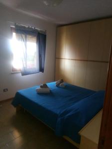 ein Schlafzimmer mit einem blauen Bett mit zwei Handtüchern darauf in der Unterkunft casa con terrazza in Stintino