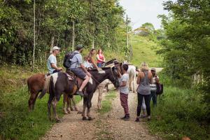 a group of people riding horses on a dirt road at Hotel Hacienda Tijax Jungle Logde in Río Dulce