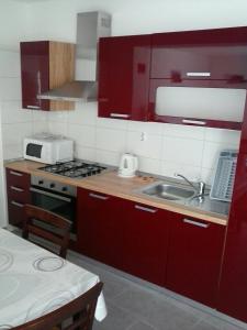 a kitchen with red cabinets and a sink at Apartmani Marić in Selce