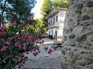 een huis met een stenen muur en roze bloemen bij Casa Rivera Río Jucar in Valdeganga