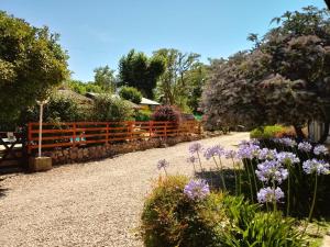 un jardín con flores púrpuras y una valla en Cabañas Don Mario en Sierra de la Ventana