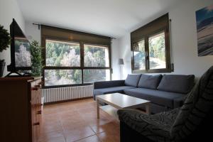 a living room with a blue couch and two windows at Pont de Toneta 3,1 Ransol, Zona Grandvalira in Ransol
