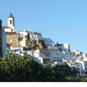 a group of white buildings on a hill with a church at Casa las tres Conchas (2) in Yunquera