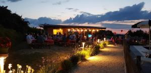 eine Gruppe von Menschen, die nachts vor einem Restaurant sitzen in der Unterkunft Agriturismo San Michele in Cossignano