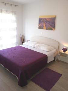 1 dormitorio con 1 cama grande con manta morada en Apartments Levanat, en Zadar