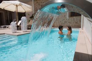 un hombre y una mujer en una piscina con una cascada en Forum Boutique Hotel & Spa - Adults Only, en Alcudia