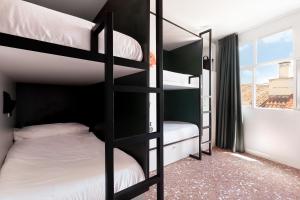 sypialnia z dwoma łóżkami piętrowymi i oknem w obiekcie 2060 The Newton Hostel w Madrycie