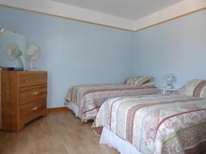 a bedroom with two beds and a dresser with two lamps at Hébergement Maison Fortier in Tadoussac