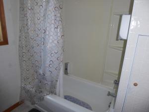 a bathroom with a shower curtain and a bath tub at Hébergement Maison Fortier in Tadoussac