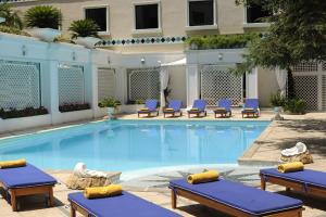 uma piscina com espreguiçadeiras e um hotel em Royal Olympic Hotel em Atenas