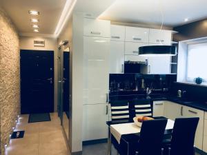 kuchnia z białymi szafkami oraz stołem i krzesłami w obiekcie Apartament Ala w Zabrzu