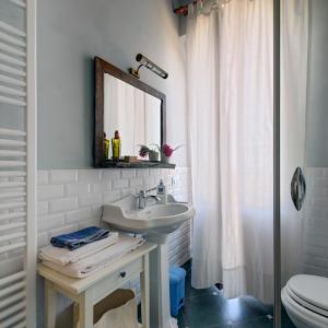 a bathroom with a sink and a toilet and a mirror at Agriturismo Agra Mater in Colmurano