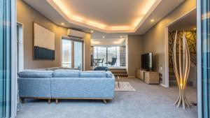 sala de estar con sofá azul y TV en Infinity Collection-Queenstown Luxury House en Queenstown