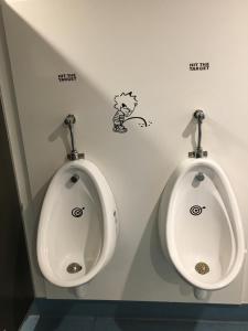 two urinals in a bathroom with stickers on the wall at Metro Adventurer Backpackers in Auckland