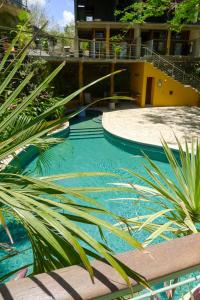 a swimming pool with a palm tree in front of a building at Amazing Studio Apartment with Pool - Close to Beach in San Juan del Sur