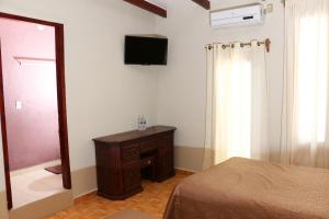 een slaapkamer met een bed en een televisie aan de muur bij Hotel La Gloria Xilitla in Xilitla