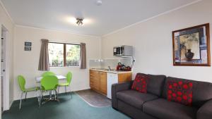 a living room with a couch and a table and a kitchen at Bk's Counties Motor Lodge in Pukekohe East