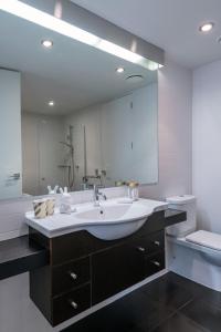 
a bathroom with a sink, mirror, and bathtub at QT Wellington Apartments in Wellington
