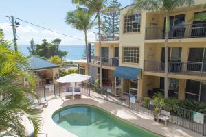 a hotel with a swimming pool in front of a building at Beachside Holiday Apartments in Port Macquarie