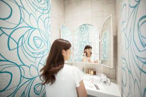 a woman standing in front of a bathroom mirror at Daiwa Roynet Hotel Nagoya Nayabashi in Nagoya