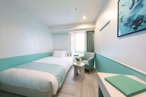 um pequeno quarto com uma cama e uma cadeira em DEL style Nagoya Nayabashi by Daiwa Roynet Hotel - former Daiwa Roynet Hotel Nagoya Nayabashi em Nagoia