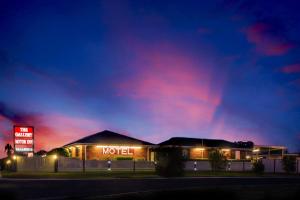 a motel with a neon sign at night at The Gallery Motor Inn in Dalby
