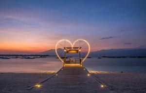 un banco iluminado por el corazón en una playa al atardecer en Vila Ombak, en Gili Trawangan