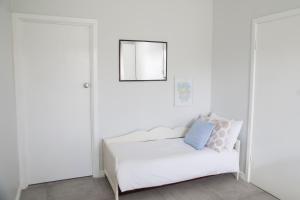 a white bedroom with a bed and a mirror at Salty Shack Lancelin in Lancelin