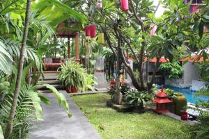 einen Garten mit roten Laternen und Bäumen und einem Pool in der Unterkunft Villa Thapae in Chiang Mai