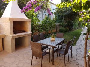 patio ze stołem, krzesłami i kominkiem w obiekcie Apartment Taja w mieście Ližnjan