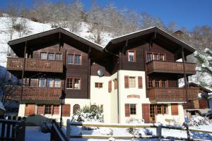 a large wooden building with balconies in the snow at Arnika in Blatten bei Naters