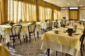 a restaurant with white tables and chairs with flowers on them at Hotel Guya in Varazze