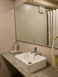 a white sink in a bathroom with a mirror at Sai Towers in Puttaparthi