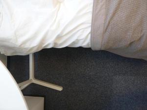 einer Ecke eines Bettes mit einem weißen Laken und einem Bettrahmen in der Unterkunft Nagoya Motoyama House B in Nagoya