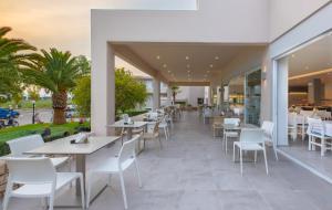 a restaurant with white tables and white chairs at Hotel Esperia in Marmari