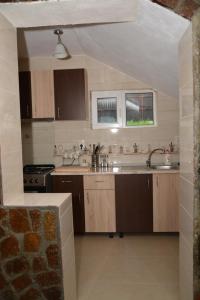 una cucina con armadi in legno, lavandino e due finestre di Bogdan si Raluca a Călimăneşti