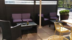 eine Terrasse mit lila Stühlen, Tischen und Stühlen in der Unterkunft La Promenade in Sierre